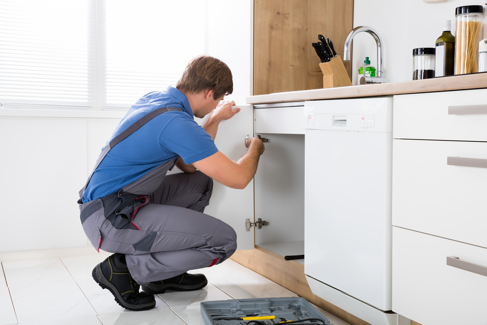 Repairman,In,Overalls,Repairing,Cabinet,Hinge,In,Kitchen